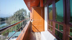 Ein Balkon mit einer Holztür, Blick auf einen Fluss und ein Gebäude mit Gründach im Hintergrund.