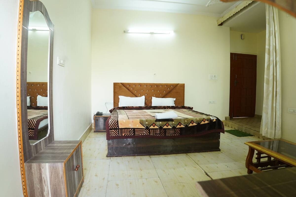 A bedroom with a bed, bedside table, mirror, and a door.