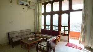 Ein Wohnzimmer mit Sofa, Sesseln, Couchtisch und großem Fenster mit Blick.