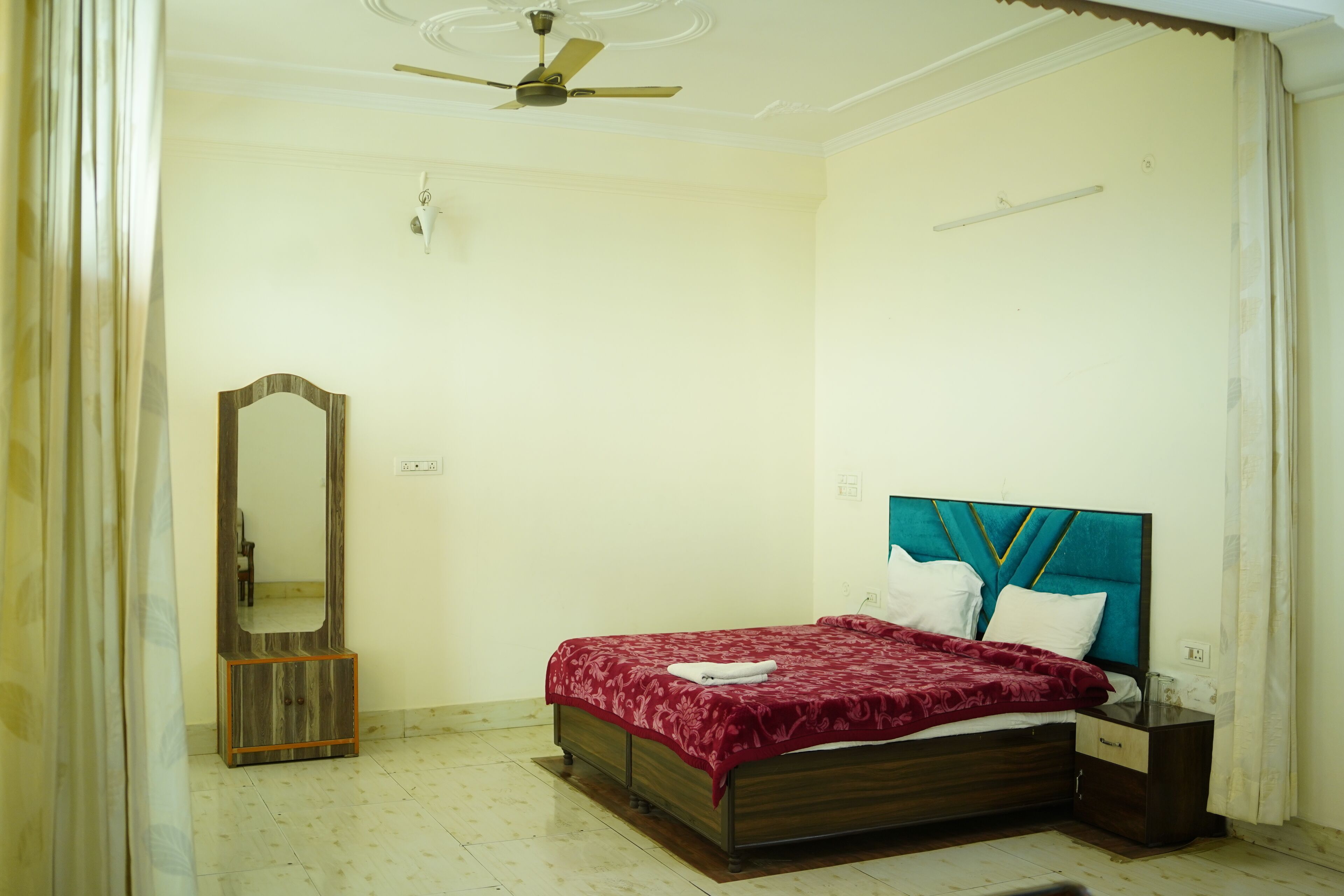 Une chambre à coucher avec un lit, une table de chevet, un miroir et un ventilateur de plafond.