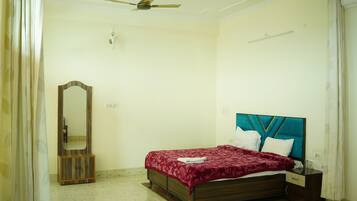 Une chambre à coucher avec un lit, une table de chevet, un miroir et un ventilateur de plafond.