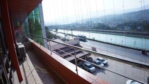 Blick vom Balkon auf einen Fluss, mit einer Brücke in der Ferne und einem Parkplatz mit Autos.