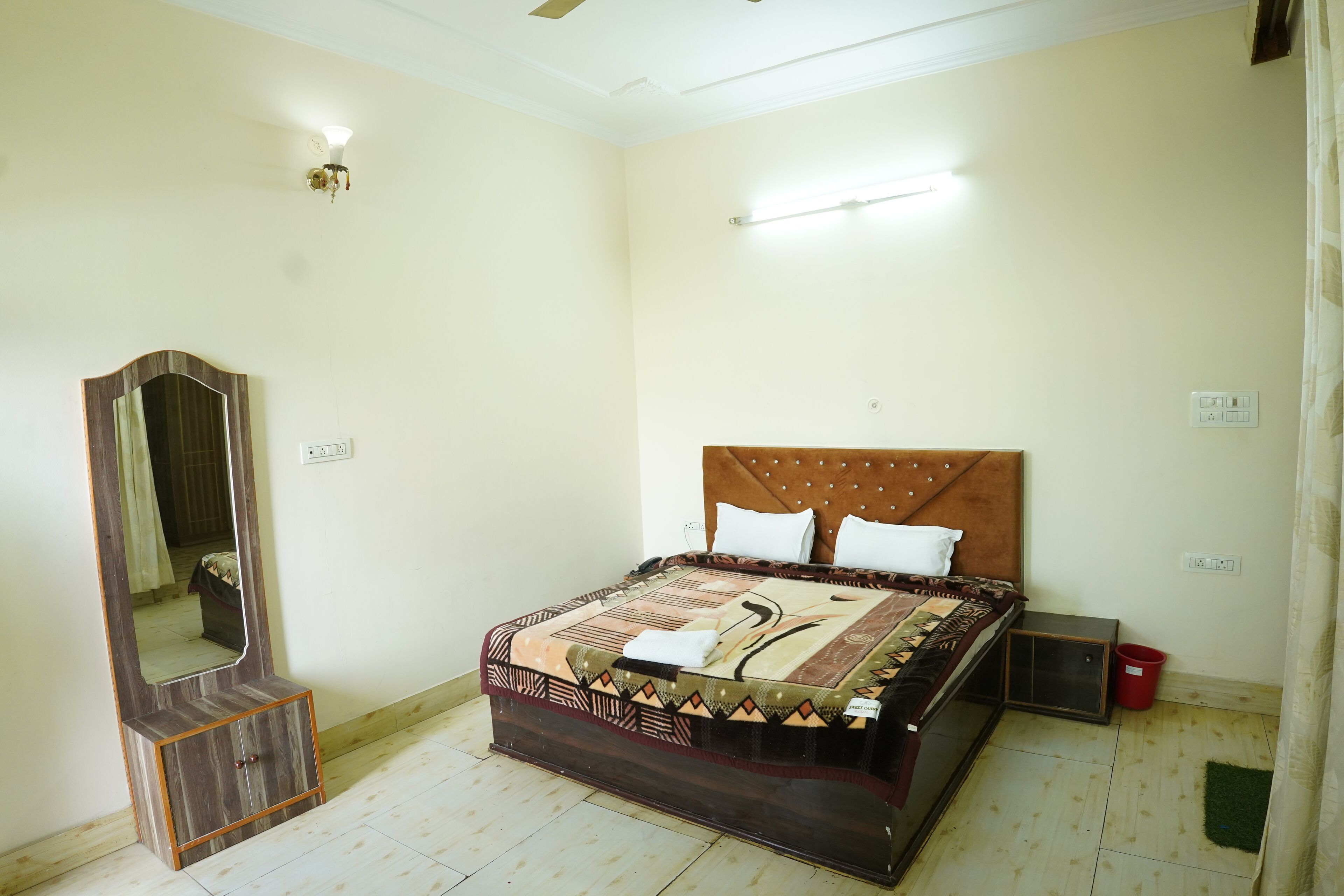 A bedroom with a bed, a wooden cabinet, a mirror, and a nightstand.