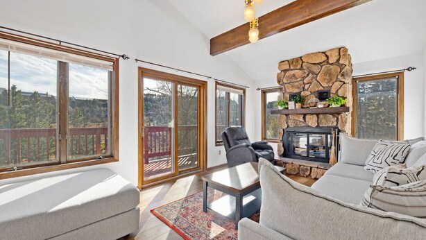 A spacious living room with a stone fireplace, large windows, and a balcony. - Lead Haven Lodge: Mountain Retreat w/ Hot tub (Lead)