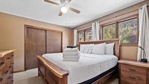 A bedroom with a wooden bed, a nightstand, a dresser, and a window with curtains. - Lead Haven Lodge: Mountain Retreat w/ Hot tub (Lead)