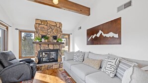 A living room with a stone fireplace, a gray sofa, and a wooden coffee table. - Lead Haven Lodge: Mountain Retreat w/ Hot tub (Lead)