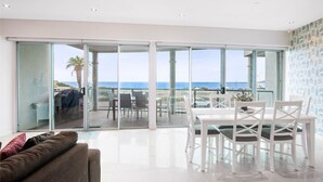 Ein modernes Wohnzimmer mit Glastür, die auf einen Balkon mit Meerblick führt.