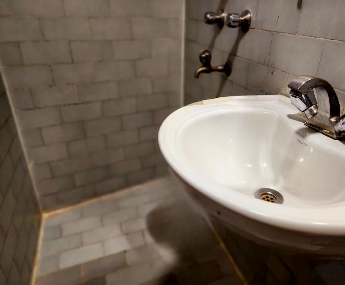 A bathroom with a white sink, a wall-mounted faucet, and a tiled backsplash.