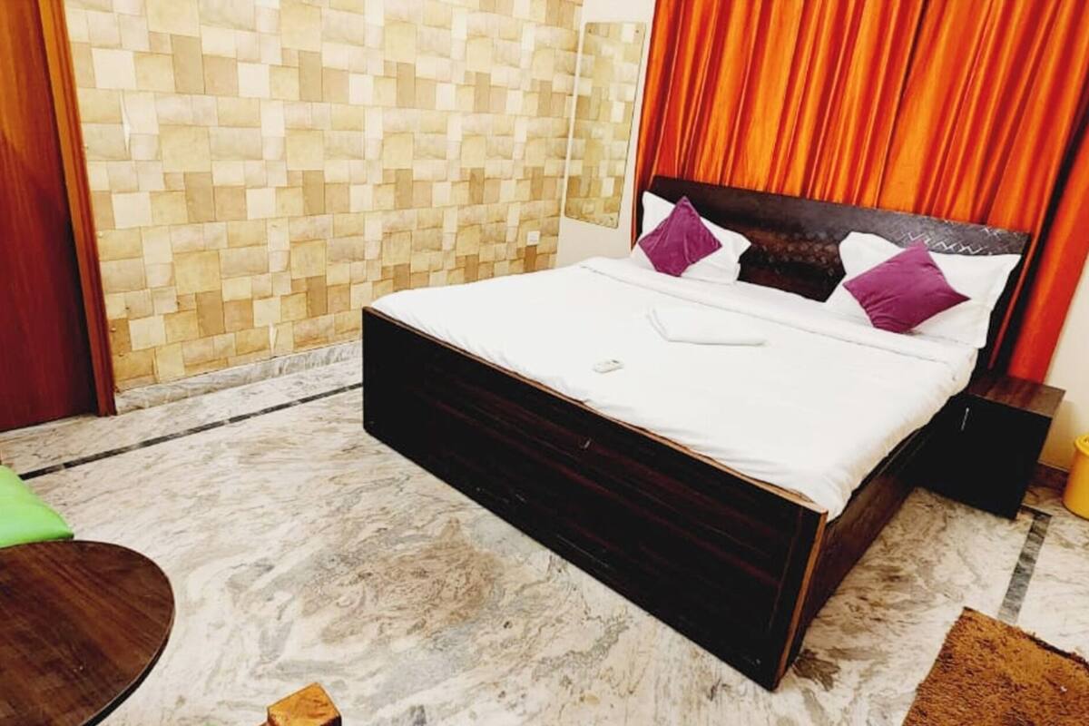 Un dormitorio pequeño y ordenado con cama, una silla verde, una mesita y un muro de azulejos.