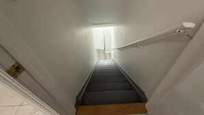 A narrow stairway with a handrail, a light fixture at the top, and a door at the bottom. - Cozy, Private Suite, Two Level Apartment With Separate Entrance (Brampton)