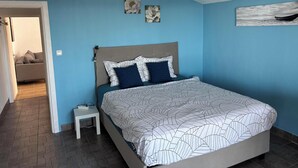 Una camera da letto con un letto, un comodino, un divano e una porta che dà su un'altra stanza.