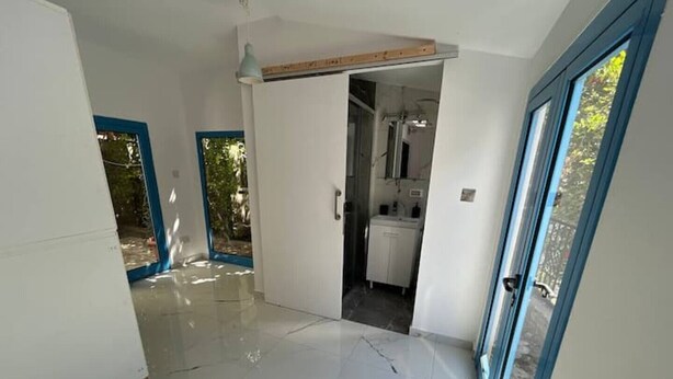 A modern interior with a tiled floor, a kitchen area, and a doorway leading to another room. - Newly Renovated Apt with Private Garden - 7 Min Walk to Beach (Paphos)