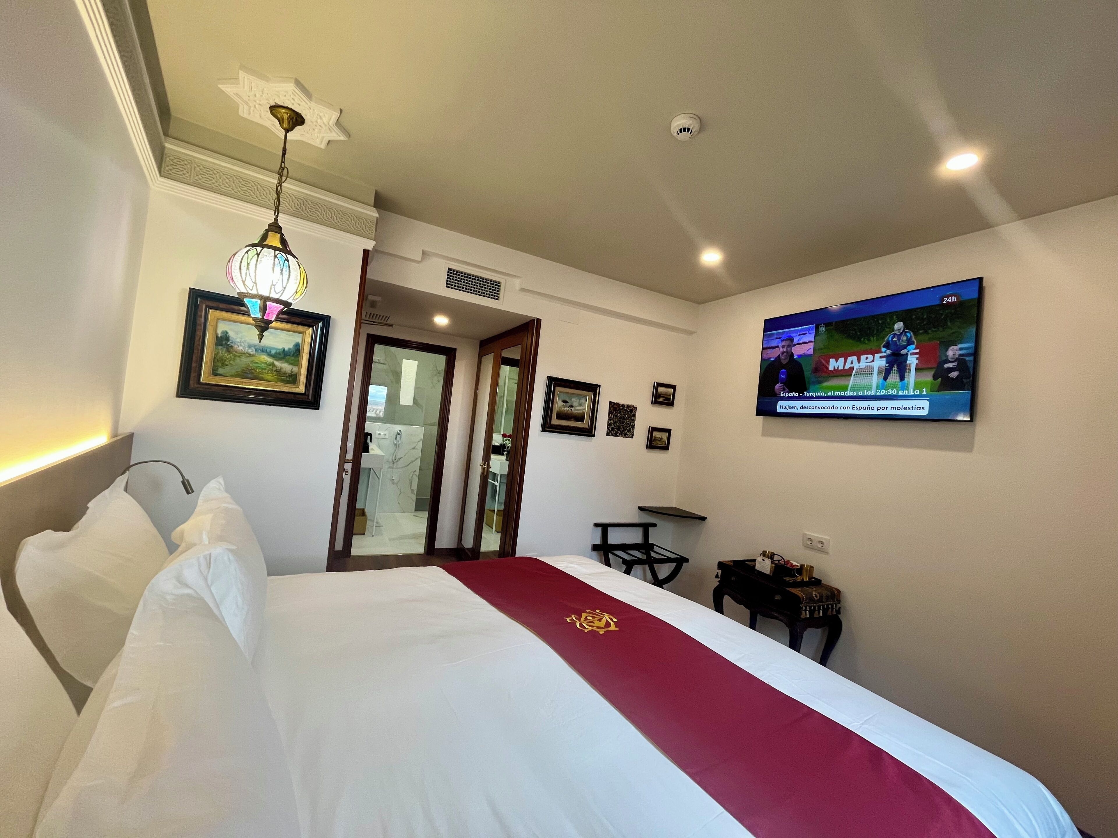 Habitació d'hotel amb llit, televisió, escriptori i mirall.