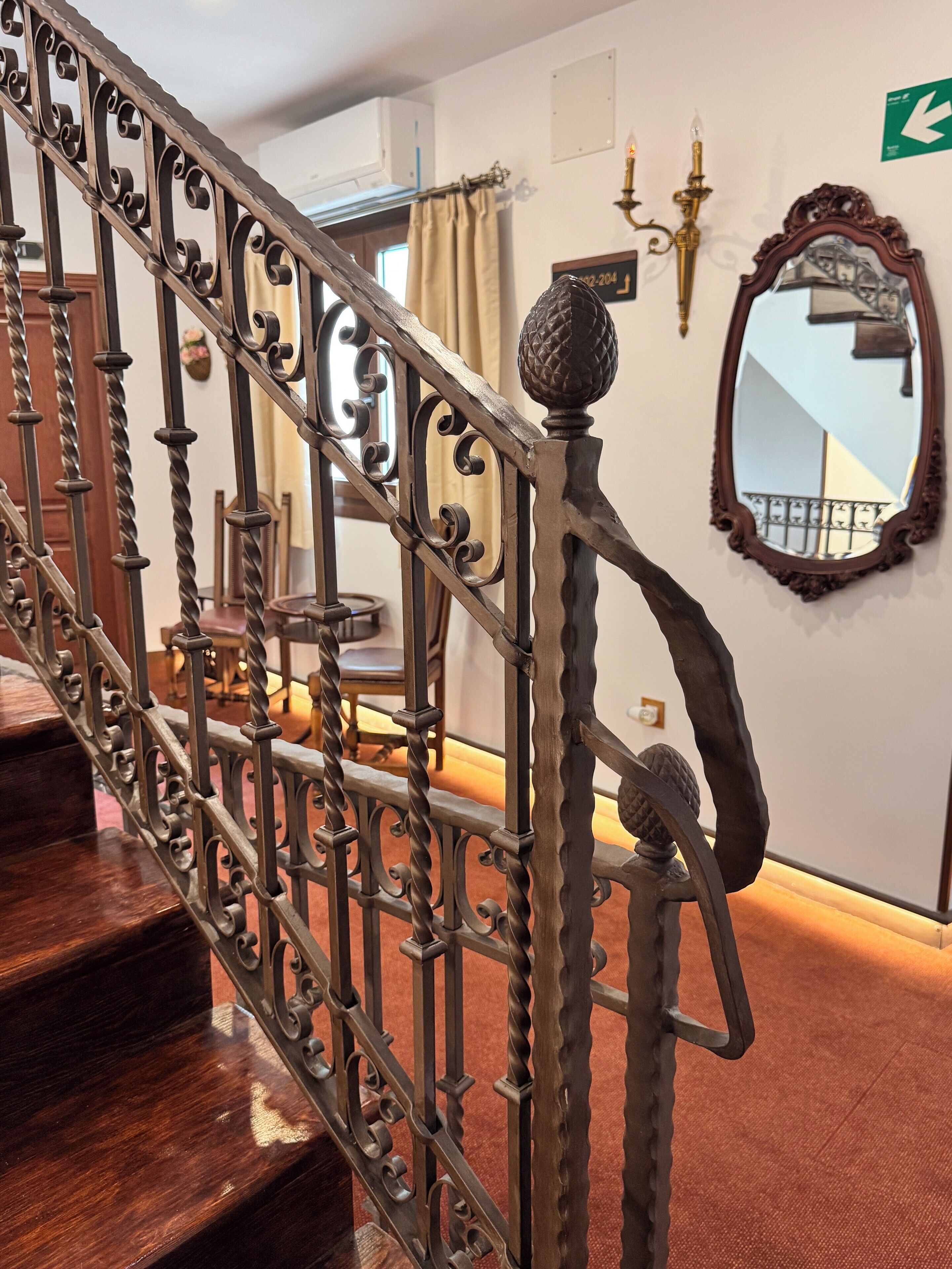 Una escalera con barandillas metálicas ornamentadas y un pasamanos de madera.