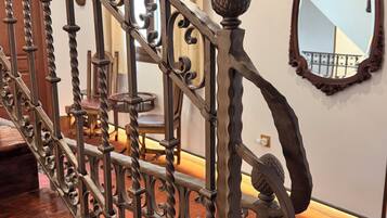 Una escalera con barandillas metálicas ornamentadas y un pasamanos de madera.