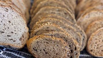 A loaf of sliced whole grain bread with visible seeds and grains, placed on a checkered cloth.