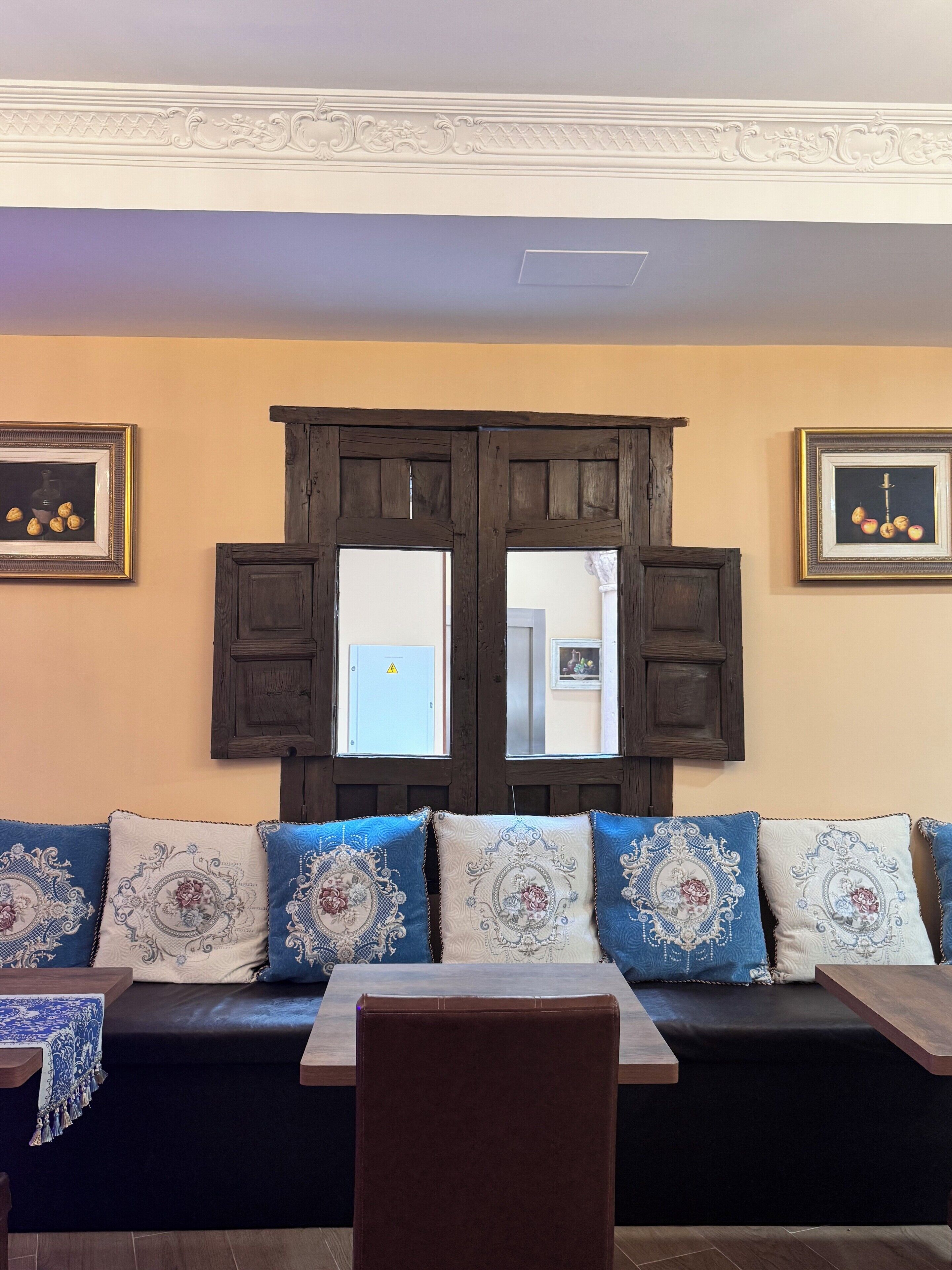 Una habitación con una puerta de madera oscura, un sofá con cojines estampados y cuadros en las paredes.