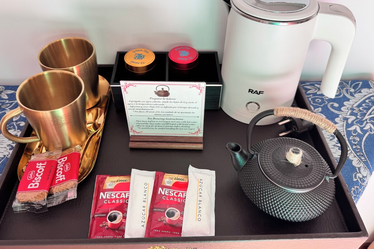 Una bandeja con equipo para preparar té, bolsitas de té, tetera y cafetera.