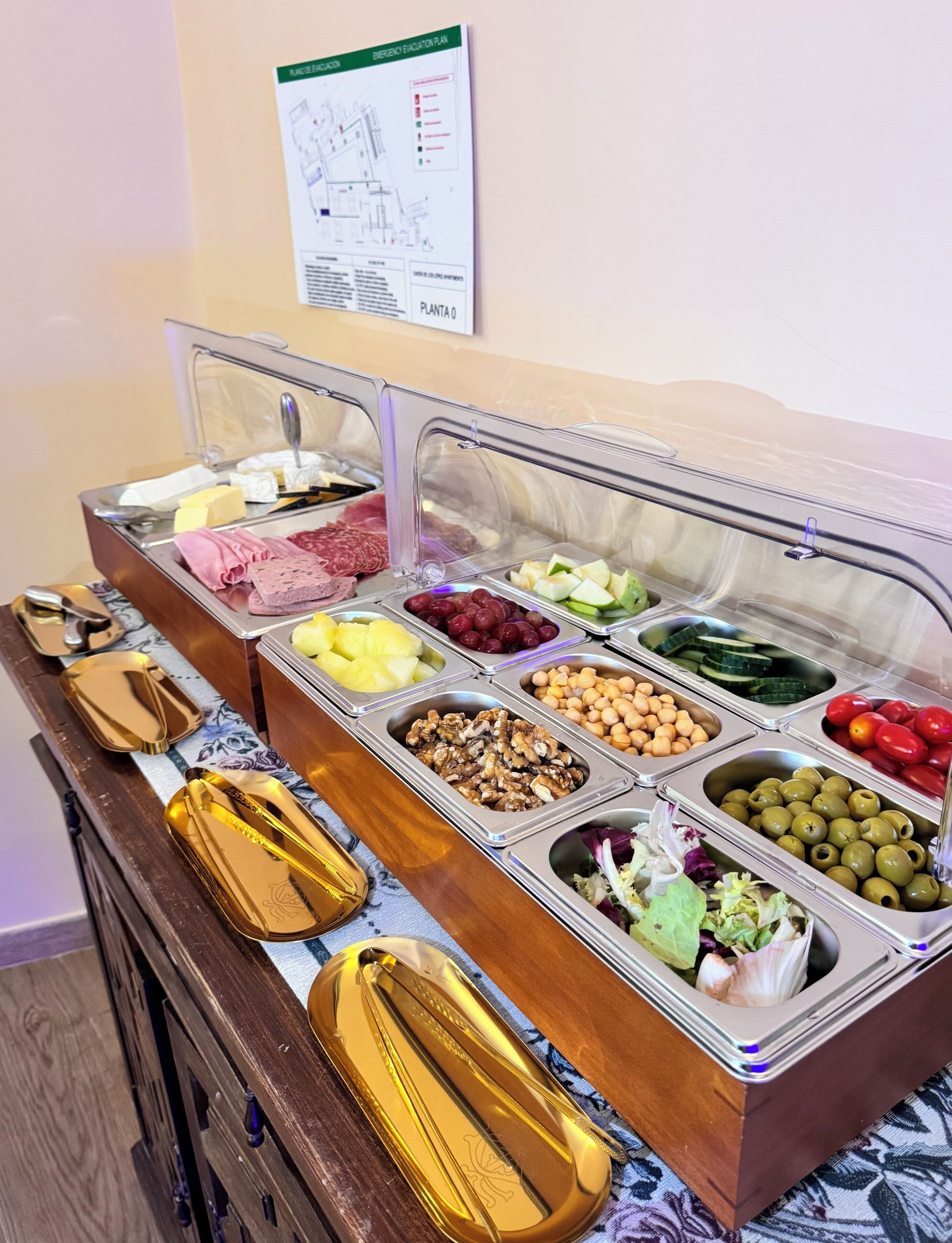 Un bufé con diversas opciones de comida, incluyendo frutas, frutos secos, quesos y carnes.