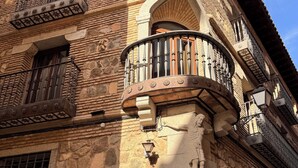 Un edificio de piedra con intrincados grabados y un balcón con barandilla de hierro forjado.