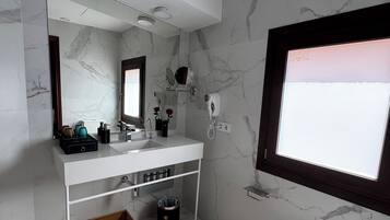 A modern bathroom with a marble backsplash, a large mirror, a vanity with a sink, and a toilet.