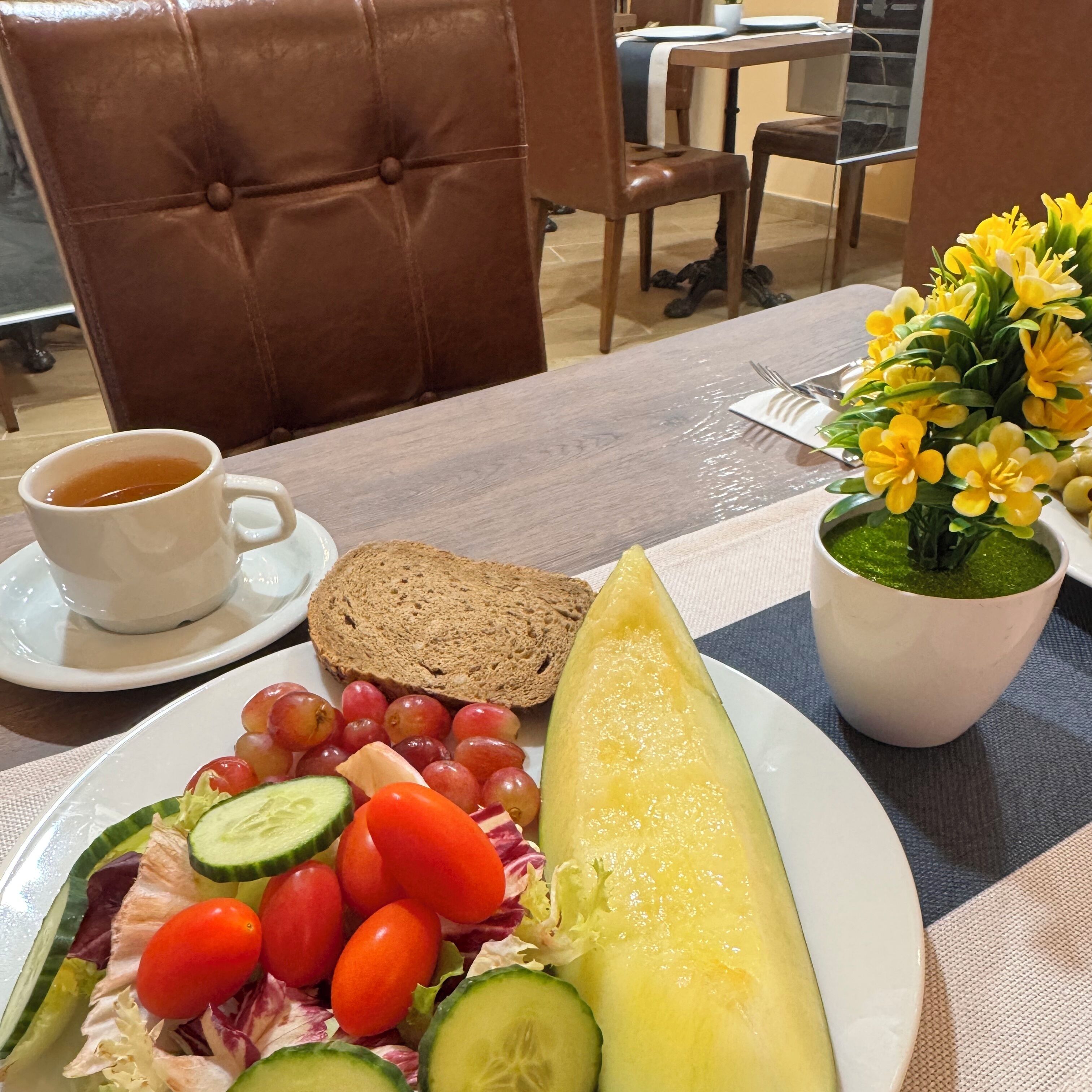 Una mesa con un plato de comida, una taza de té y una planta en maceta.