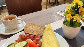 Una mesa con un plato de comida, una taza de té y una planta en maceta.