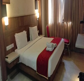 Ein Hotelzimmer mit einem großen Bett, einem Nachttisch, einem Sessel und einem Schreibtisch.