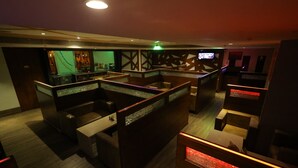 A modern bar area with wooden furniture and a glass partition. - Breeze Palace (Karur)