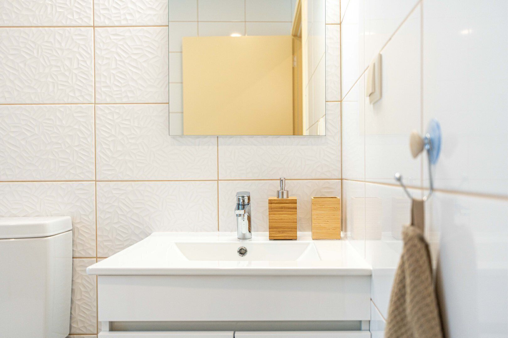 A bathroom with a white sink, a mirror, and a towel rack.