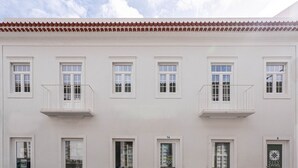 A white building with multiple windows and balconies, featuring a tiled roof and a flat facade. - City Oasis - Suite A (City Centre) (Ponta Delgada)