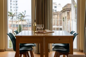 A dining area with a wooden table, six chairs, a bottle of white wine, and glasses on a tray. - City Oasis - Suite C (City Center) (Ponta Delgada)