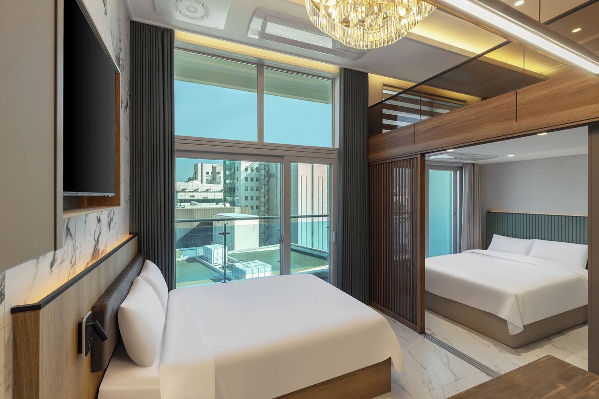 Une chambre d’hôtel moderne avec un grand lit, une télévision et une vue sur la ville.