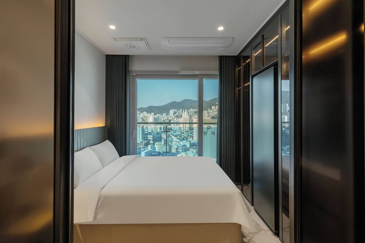 Une chambre d’hôtel avec un grand lit, une vue sur la ville et un design moderne.