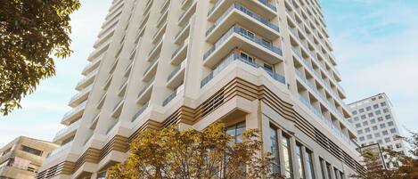 A tall, modern building with a distinctive angular design, featuring multiple balconies and large windows.