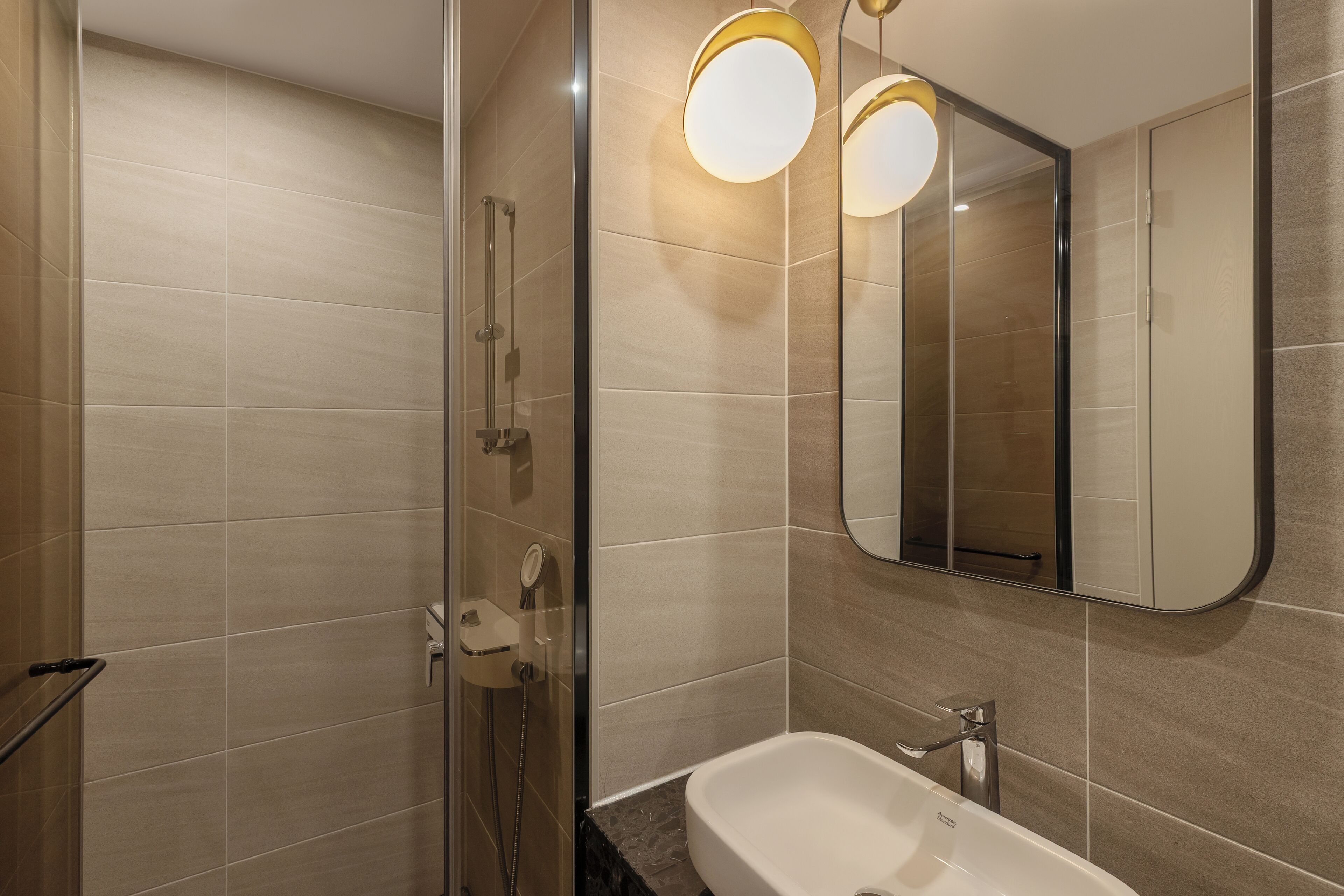 Un bagno moderno con cabina doccia in vetro, lavandino bianco e un ampio specchio.