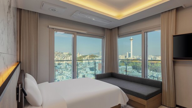 A modern hotel room with a large bed, a seating area, and a TV. - NewCZ Nampo Hotel (Busan)