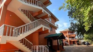 A multi-story building with a central staircase, a covered entrance, and a paved courtyard. - Kawari Resort (Gokarna)