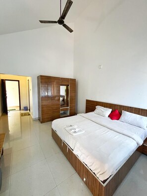 Un dormitorio moderno con una cama grande, un armario de madera y un ventilador de techo.
