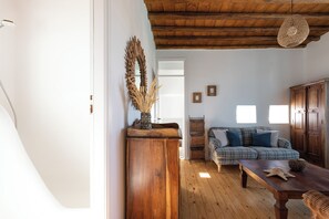 Ein gemütliches Wohnzimmer mit Holzboden, einem Holztisch, einem Karo-Sofa und einem Holzschrank.