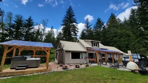 A house with a solar panel roof, a hot tub, and a barbecue area. - Sasquatch Sanctuary | New to market! (Packwood)