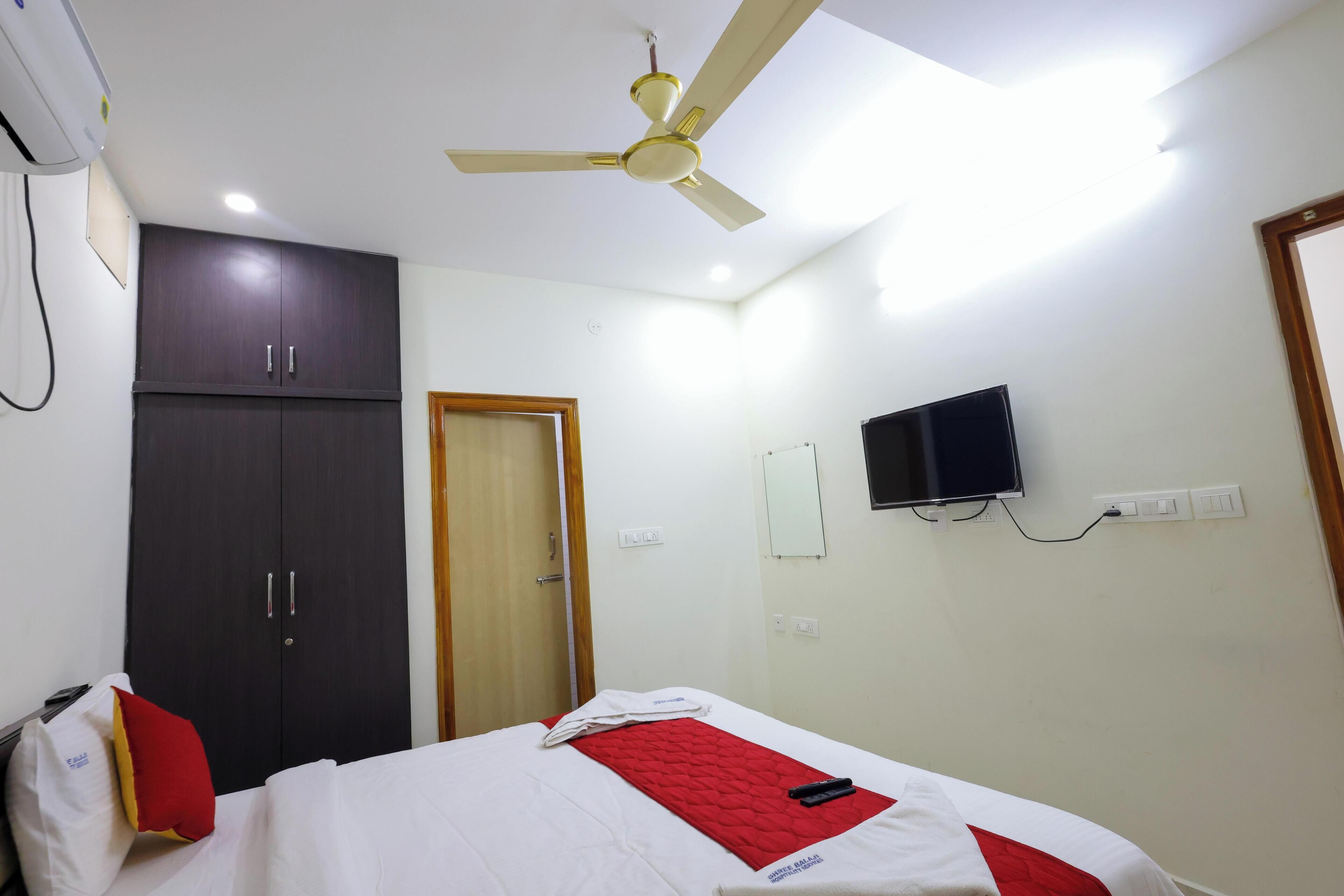 A hotel room with a bed, a wardrobe, a ceiling fan, a TV, and a wall-mounted air conditioner.