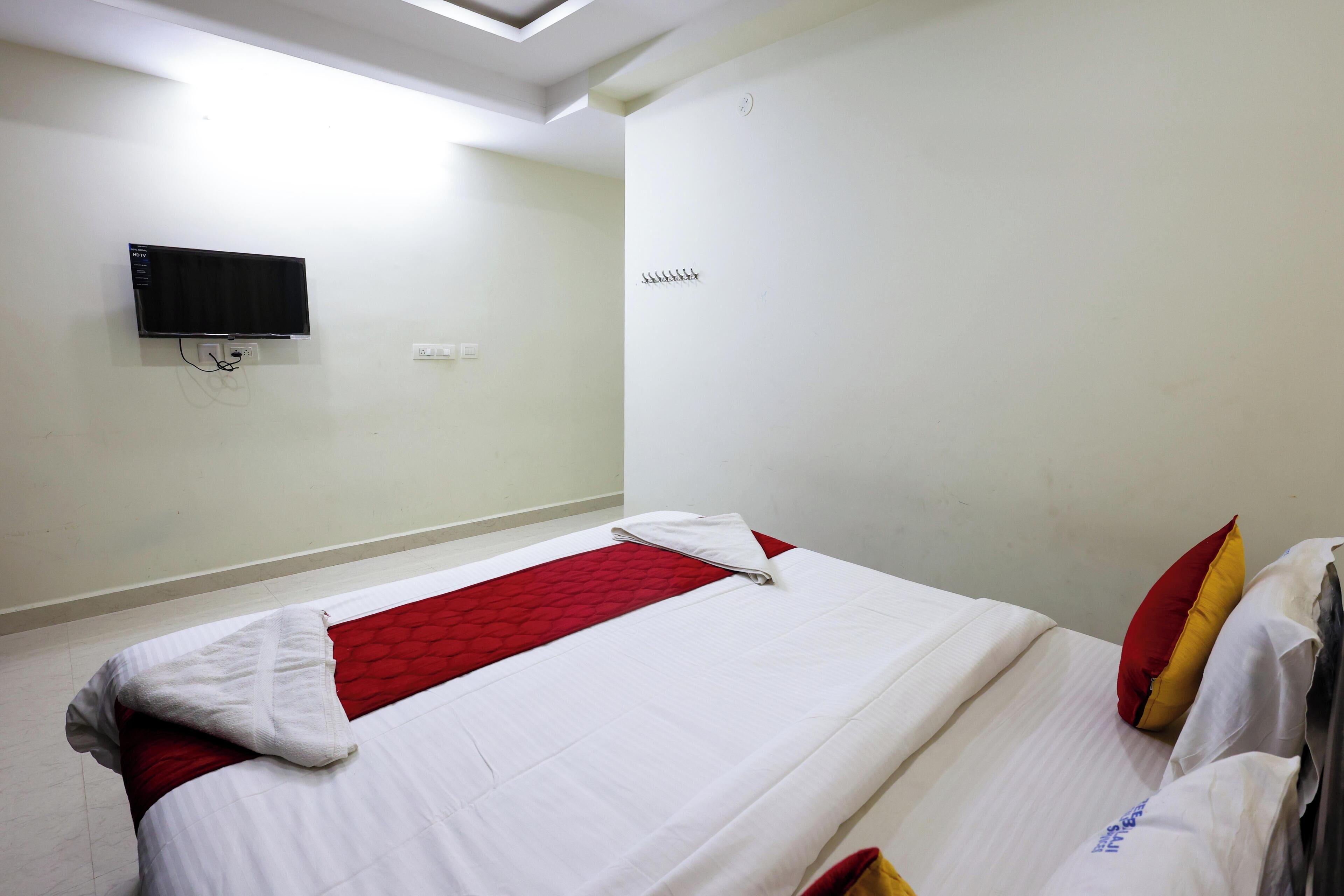 Een hotelkamer met een bed, een flatscreen televisie aan de muur en een klein plankje met haken.
