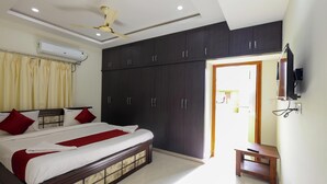 A bedroom with a bed, dark cabinets, a ceiling fan, an air conditioner, and a TV. - SBHS Homestay- Venkatadri (Tirupati)