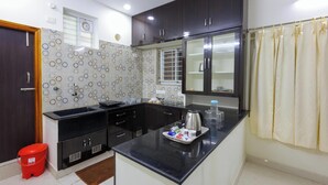 A modern kitchen with dark cabinets, a black countertop, and a breakfast tray. - SBHS Homestay- Venkatadri (Tirupati)