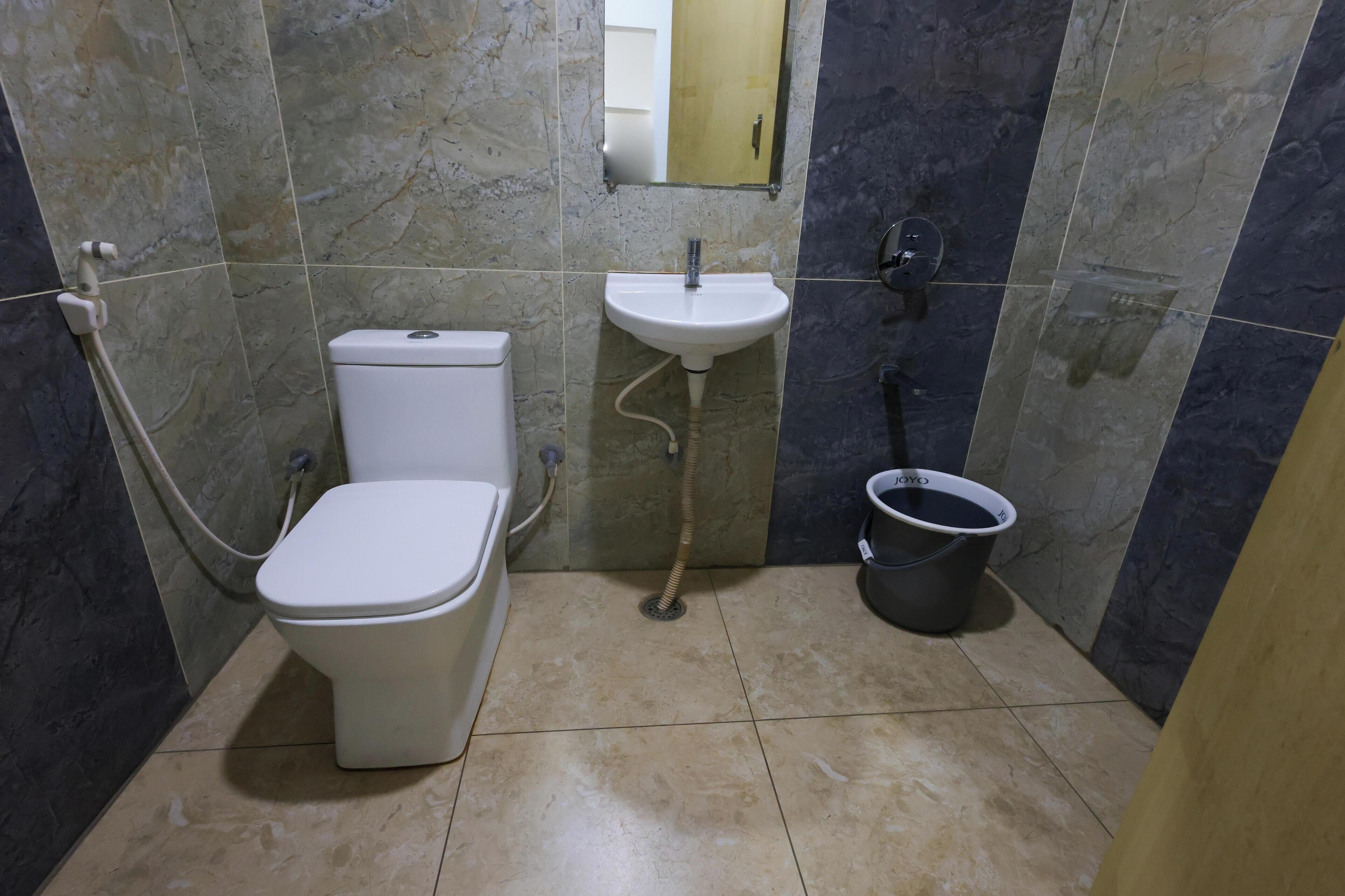 Un baño con inodoro, lavabo y un cubo.