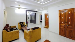 A spacious living room with a ceiling fan, a sofa set, a dining table, and a wooden wardrobe. - SBHS Homestay- Venkatadri (Tirupati)