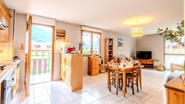 A spacious living area with a dining table, kitchen, and a TV in the background. - Apartment in Thones With Mountain Views (Thones)