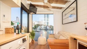 A compact kitchen with a washing machine, a wooden countertop, and a view of the city through large windows. - Tiny Home in the heart of Broadbeach-River Views! (Broadbeach Waters)