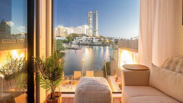 A modern living room with a view of a city skyline and a body of water. - Tiny Home in the heart of Broadbeach-River Views! (Broadbeach Waters)